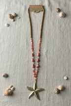 Sautoir bohème femme perles bois rose avec pendentif étoile dorée, vue à plat