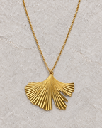 Vue retouchée du pendentif feuille de ginkgo doré et de ses nervures sur pierre claire.