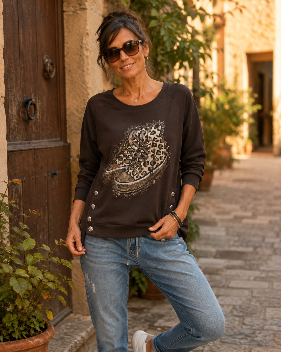 Sweat Bari chocolat porté avec jean, motif sneakers léopard et strass dans une ruelle italienne