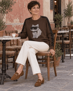 Femme assise en terrasse avec le sweat Catty Chic chocolat et un jean écru