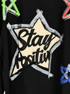 Détail du flocage Stay Positive et des contours argentés du sweat Eva