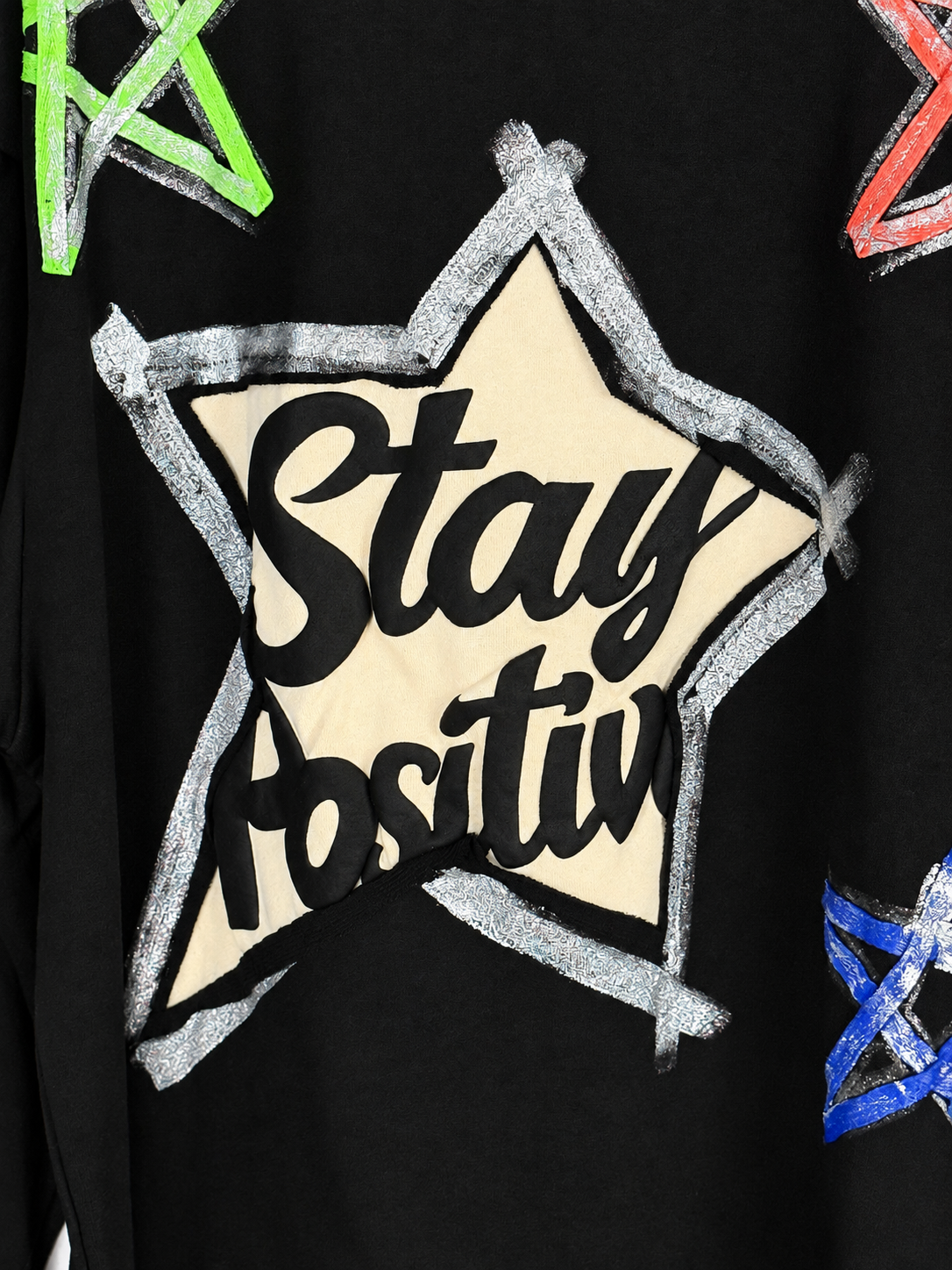 Détail du flocage Stay Positive et des contours argentés du sweat Eva