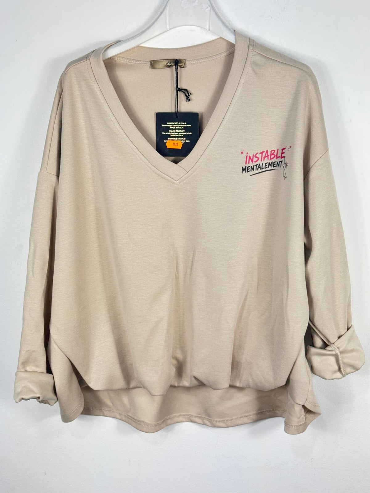 Sweat Instable beige sur cintre, grand col V, manches longues et devant resserré.