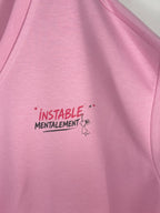 Gros plan du message Instable mentalement et du petit personnage sur le sweat rose.