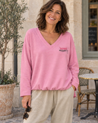 Sweat Instable rose porté avec le jogging Lou beige, col V, petit motif côté cœur et devant blousant laissé libre.