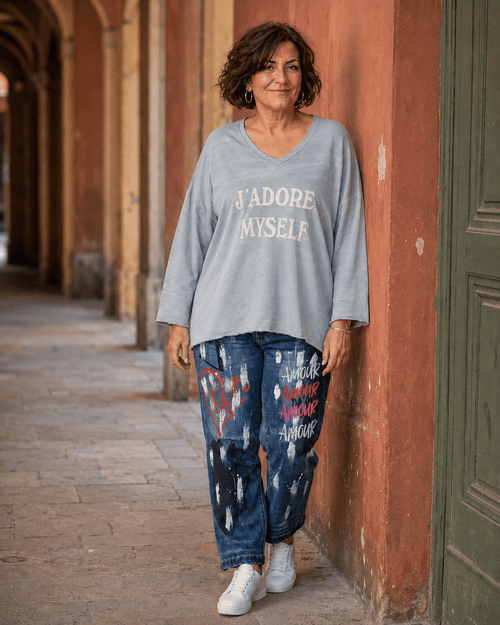 Femme en taille 46/48 portant le sweat gris J’adore Myself et le jean Amore dans une ruelle italienne