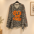 Sweat Let’s Go léopard beige sur cintre, col V, inscription LET’S DO THIS orange et boutons assortis sur les manches