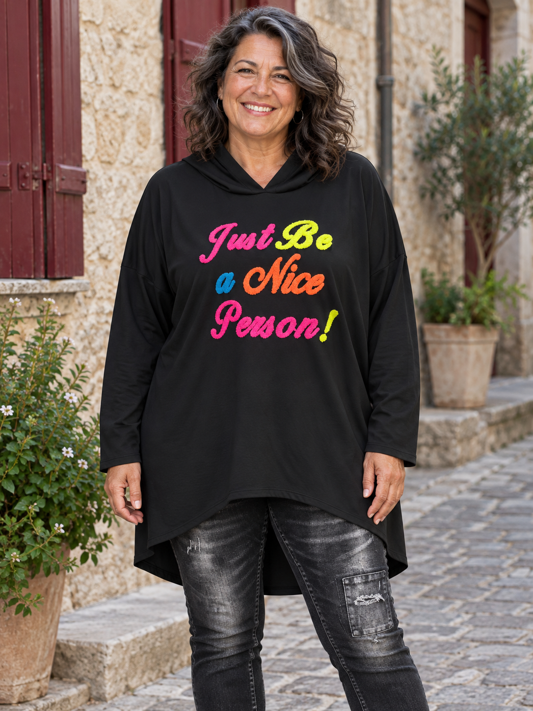 Sweat long Morgane noir à capuche porté, broderie multicolore Just Be a Nice Person et dos plus long. 