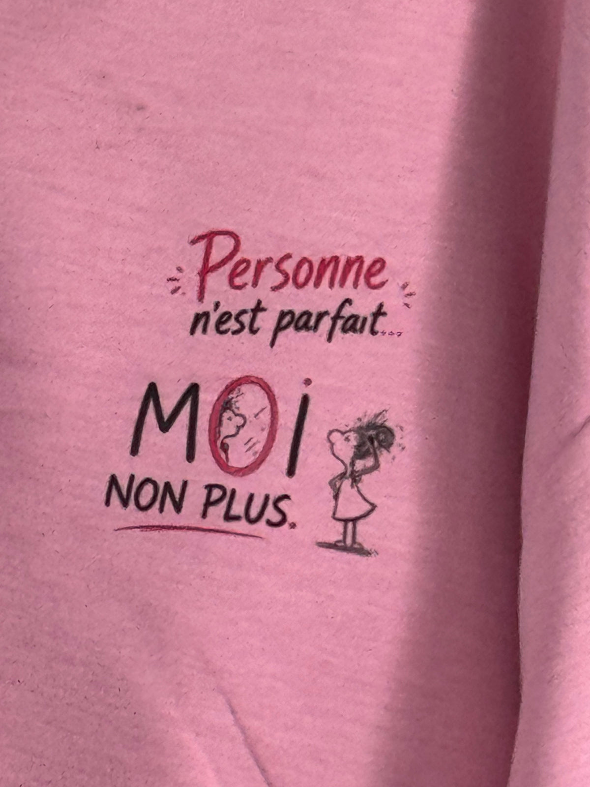Gros plan original du petit motif côté cœur du sweat rose : Personne n’est parfait… MOI NON PLUS, avec une illustration au miroir.