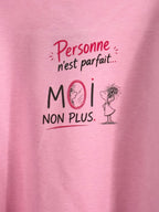 Gros plan original du grand motif au dos du sweat rose, avec le message Personne n’est parfait… MOI NON PLUS et la petite femme au miroir.
