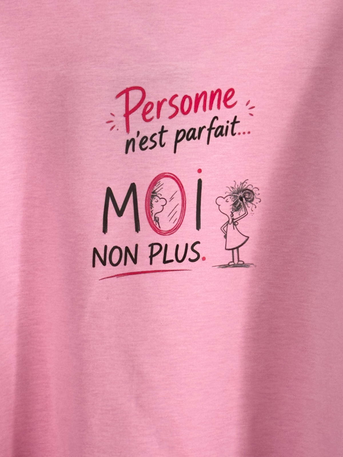 Gros plan original du grand motif au dos du sweat rose, avec le message Personne n’est parfait… MOI NON PLUS et la petite femme au miroir.