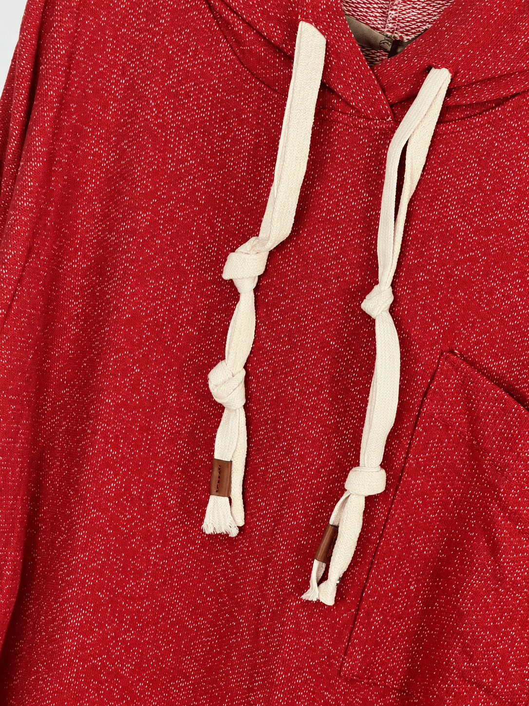 Détail du sweat rouge chiné, cordons écrus noués avec pattes brunes et bord de la poche décalée.