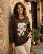 Femme portant le sweat Snoopy chocolat à strass avec pantalon écru dans une ruelle italienne
