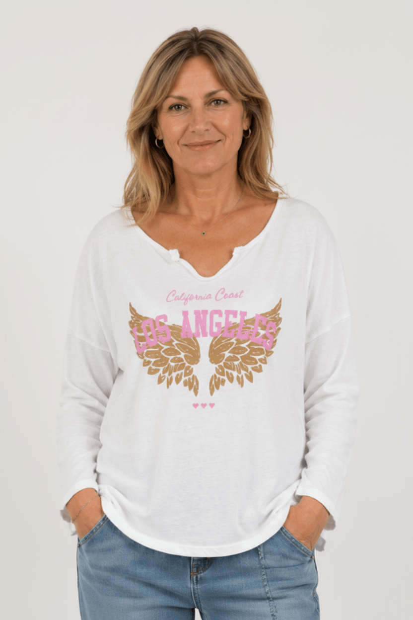 Tee-shirt femme blanc imprimé Los Angeles rose et ailes dorées porté par une femme naturelle de 50 ans vue de face