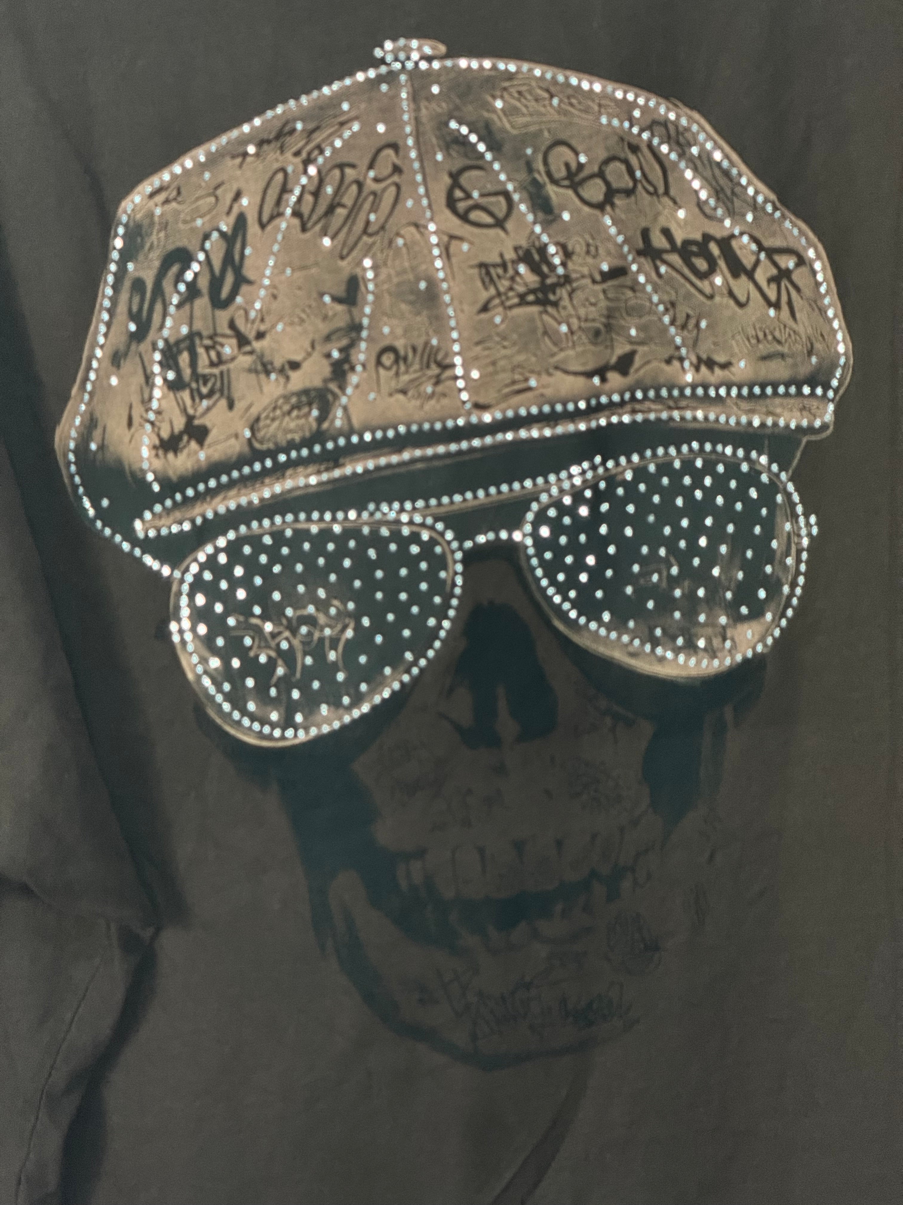 Détail du crâne à casquette graffée et lunettes pavées de strass du Tee-shirt Rebel