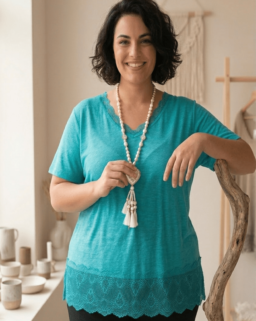 Top turquoise en viscose avec large bordure dentelle, porté avec un sautoir perles blanches et cœur nacré.