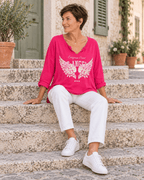 Top Los Angeles fuchsia avec pantalon blanc, silhouette assise sur un escalier