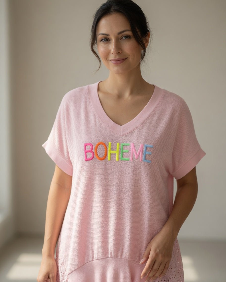 Femme de 45 à 50 ans portant une tunique bohème rose BOHEME avec pantalon blanc, bijoux discrets