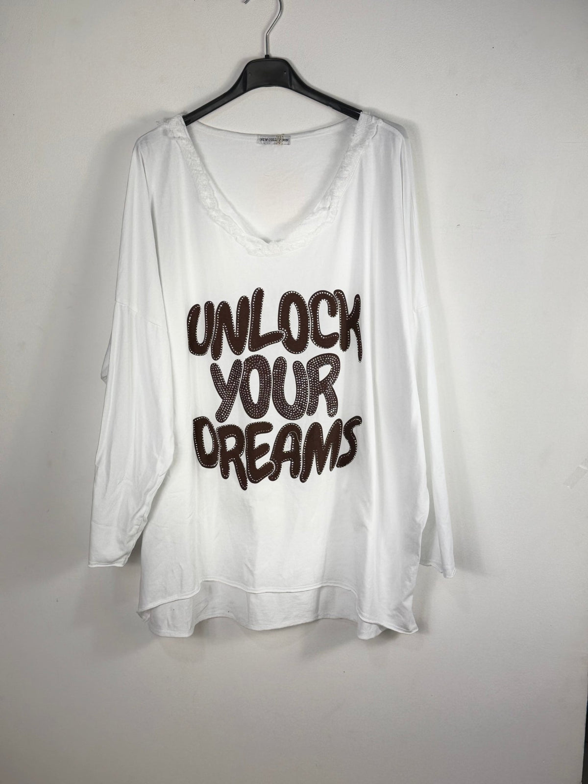 Tunique blanche sur cintre, col V effrangé et message brun Unlock Your Dreams.