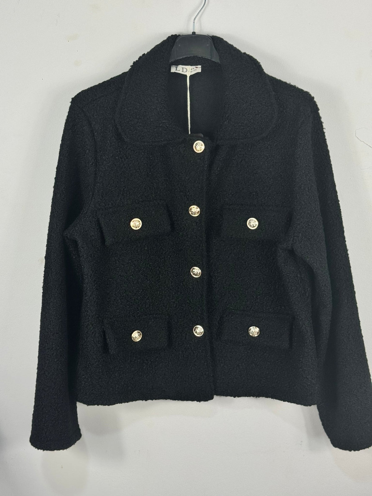 Veste Giulia bouclée noire sur cintre, boutons dorés et coupe droite
