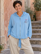 Sofia portant la veste bleu ciel Moi non plus à capuche avec le jogging Lou beige, vue de face